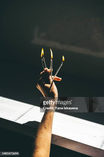 a hand of an anknown person holding burning candles in the harsh sunlight as a symbol of an insight - knowledge is power stock pictures, royalty-free photos & images