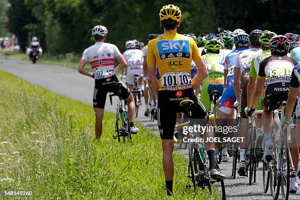 The pack rides past overall leader's yellow jersey, British Bradley Wiggins, urinating during the 194,5 km and tenth stage of the 2012 Tour de France...