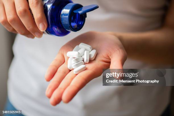 woman's hands palm holding vitamin white pills and medicines bottle, close-up - calcita mineral fotografías e imágenes de stock