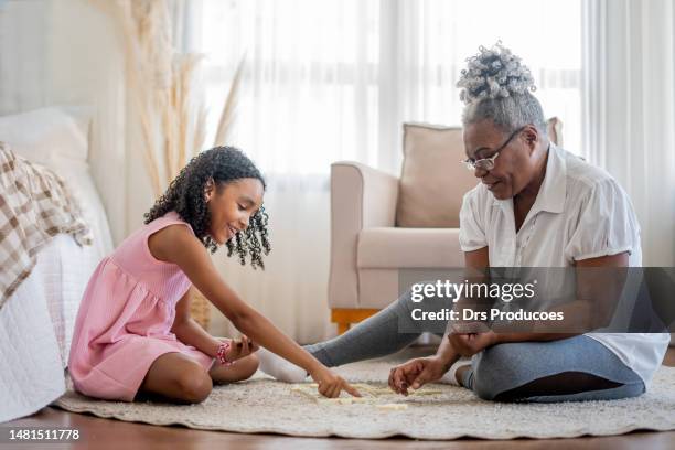 grandmother and granddaughter playing dominoes - domino stock pictures, royalty-free photos & images