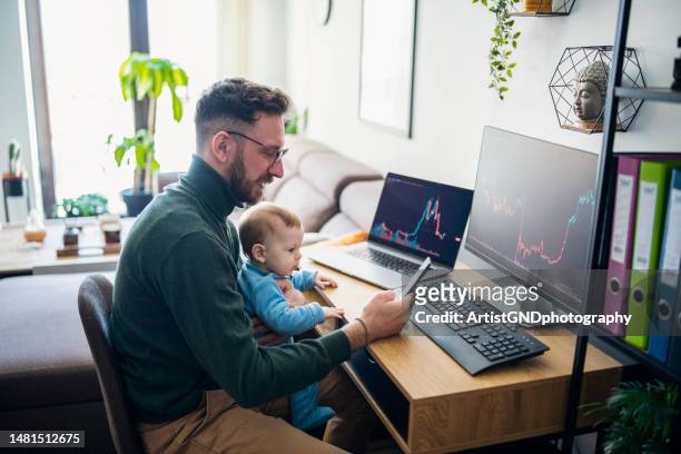 man looking at currency trading app on his smart phone from his home office. - baby supplies stockfoto's en -beelden