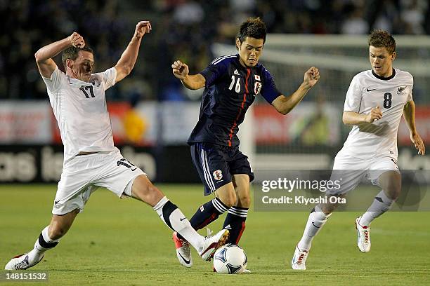 Hotaru Yamaguchi of Japan is challenged by Adam McGeorge and Michael McGlinchey of New Zealand during the international friendly match between Japan...