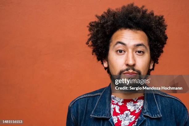 latino non-binary person with afro hairstyle raising an eyebrow and looking at the camera - levantar las cejas fotografías e imágenes de stock
