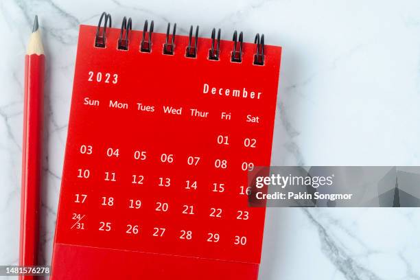 top view of the calendar desk 2023: december is the month for the organizer to plan and deadline with a red pencil against a white marble background. - december stock pictures, royalty-free photos & images