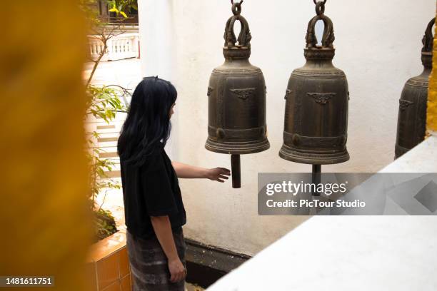 women tourist touching bells in pagoda - buddhist bells stock pictures, royalty-free photos & images