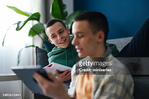 An Anonymous Teenager Using A Digital Tablet With His Twin Brother At Home