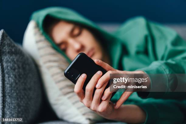 close up photo of teenager hands using a mobile phone at home - cyberbullying stockfoto's en -beelden