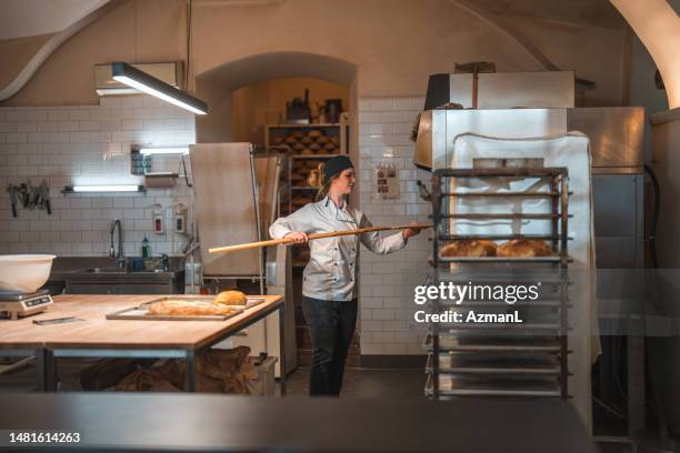 mid adult caucasian female baker handling freshly baked goods - baker stock pictures, royalty-free photos & images