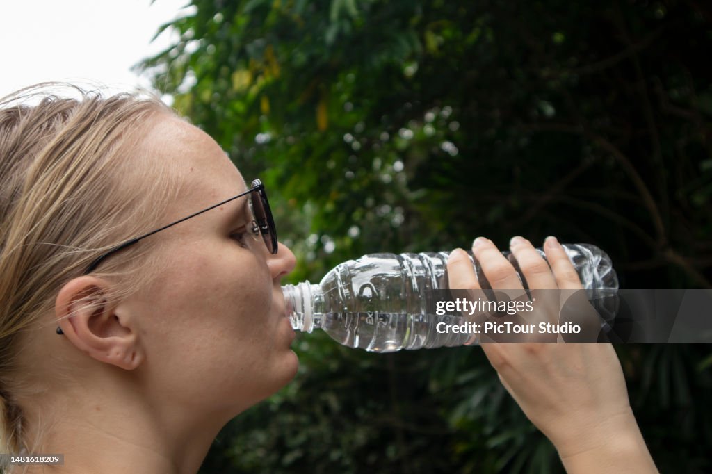 Mujer bebiendo agua de una botella de plástico