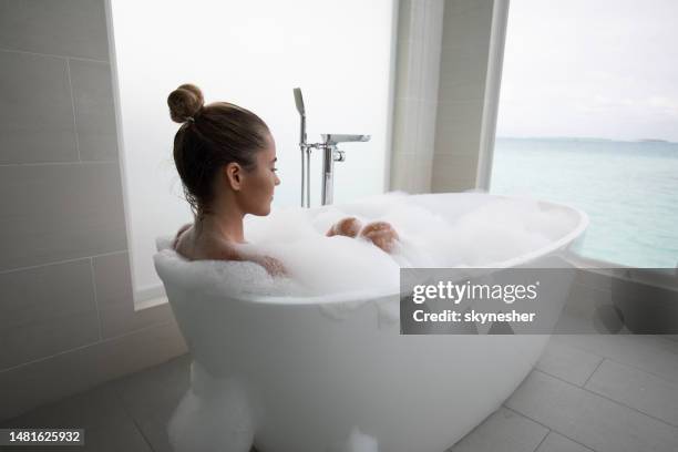 young relaxed woman enjoying in bubble bath. - woman bath tub wet hair stock pictures, royalty-free photos & images