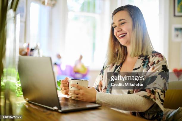 laptop, coffee and laughing woman in home for social media, funny meme and online browsing. tea, remote worker and happy person and professional with computer for comedy, comic and web scrolling. - searching the web stockfoto's en -beelden
