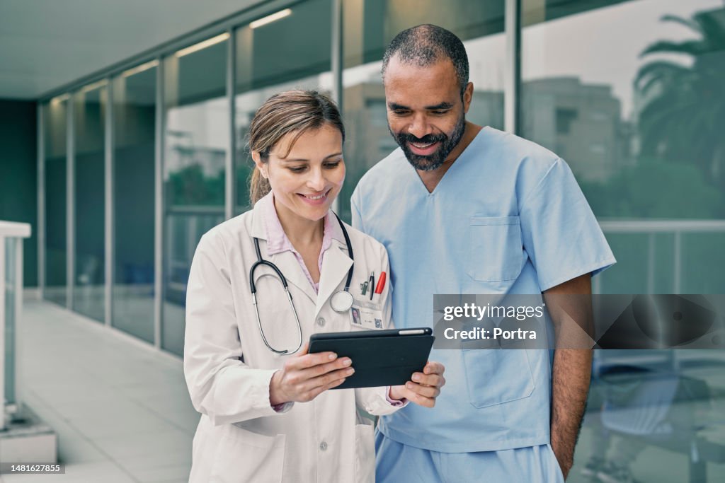 Doctor and nurse discussing over a medical report on digital tablet in hospital