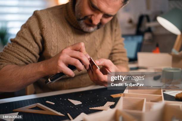 arquitecto con bisturí cortando piezas de cartón para modelo arquitectónico - esterilla para cortar fotografías e imágenes de stock