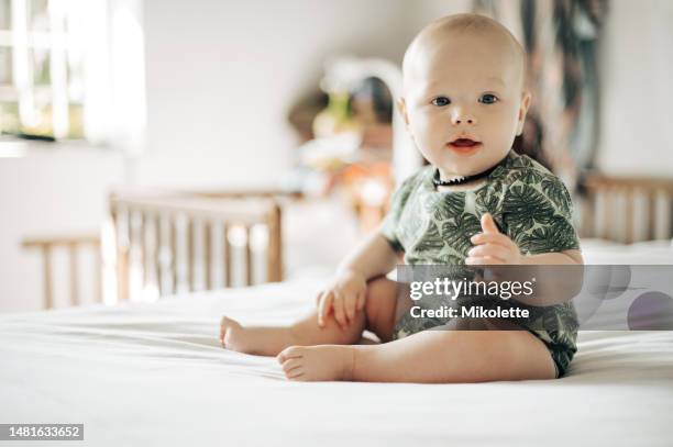 baby boy, bed and smile in home with excited face, attention and looking with health, youth and childhood. young infant, bedroom and development in house, apartment and child wellness in morning - modern baby nursery stock pictures, royalty-free photos & images