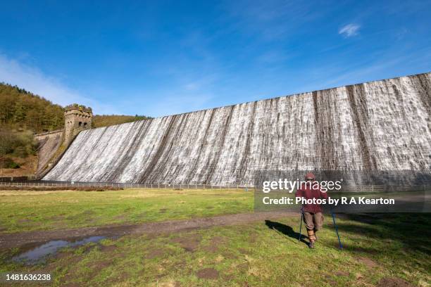 mature woman with walking poles at derwent dam, peak district, derbyshire, england - derwent reservoir stock pictures, royalty-free photos & images