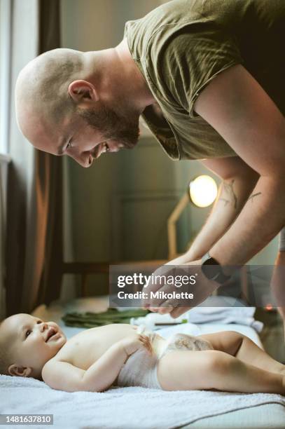 bambino, letto e pannolino con un padre che cambia il pannolino del suo bambino nella loro casa durante la cura dei bambini. neonati, cambio e pulizia con un papà responsabile che si prende cura del suo neonato in casa - adult baby boy diaper change foto e immagini stock