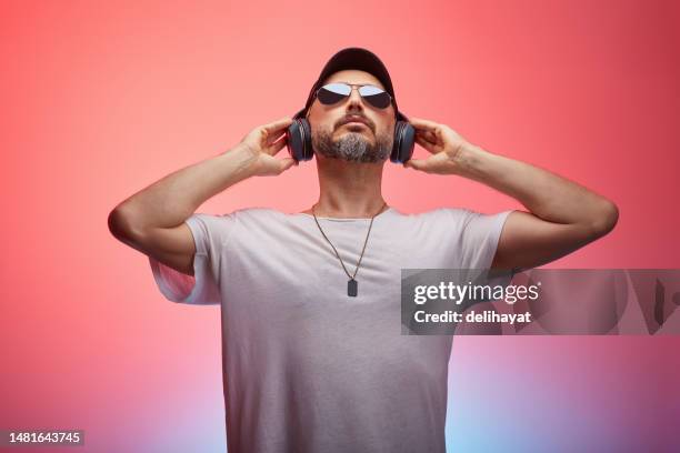 handsome casual and attractive man listening to music from headphones in joy against colorful background - dj imagens e fotografias de stock