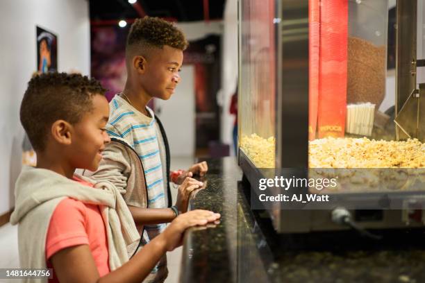 two brazilian boys buying popcorn at concession stand in a movie theater - good boy premiere stock pictures, royalty-free photos & images