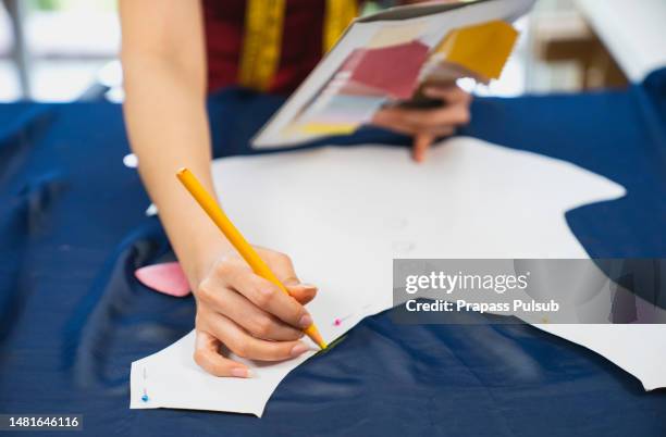 woman measuring fabric in fashion design studio - saum muster stock-fotos und bilder