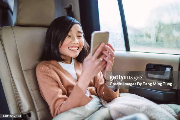 teenage girl using her smartphone joyfully while travelling in car - ip phone stock pictures, royalty-free photos & images