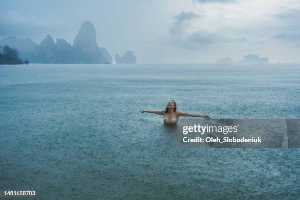 femme nageant dans la mer sous la pluie - phuket beach photos et images de collection