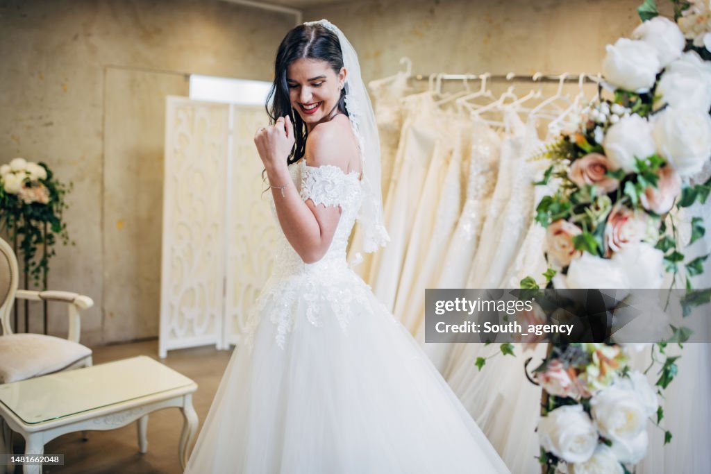 Sposa che prova l'abito da sposa nel negozio da sposa