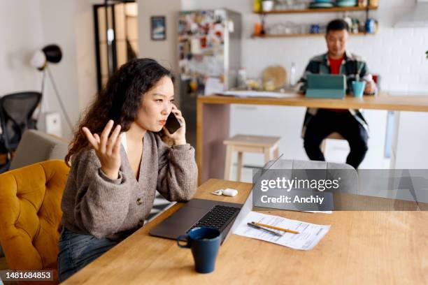 woman talking on a smartphone while working from home - couple working from home stock pictures, royalty-free photos & images