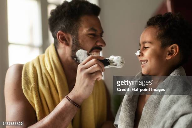young father showing his little son how to shave. - shaving cream stock-fotos und bilder