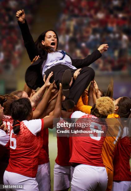 the soccer coach of a red team is lifted up by her team into the air in celebration. - great effort stock pictures, royalty-free photos & images