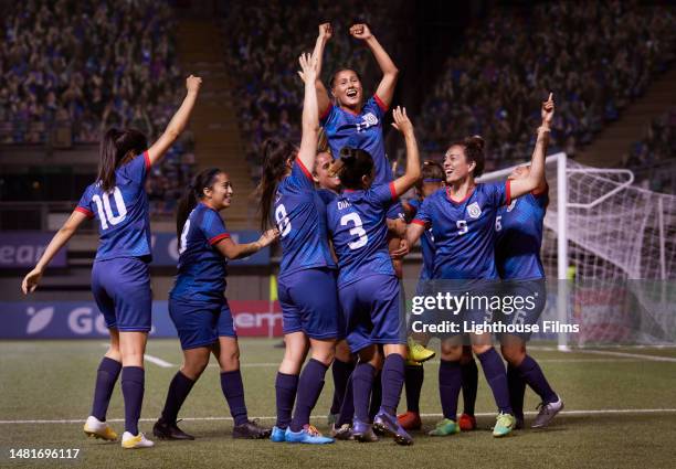 a young latina woman is lifted in celebration by a team of female soccer players. - fan women stock-fotos und bilder