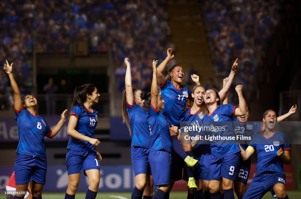 A team of female soccer players joyously react to a play during a sports competition.
