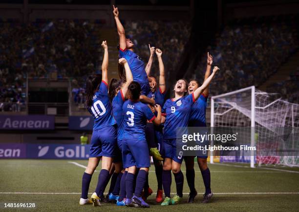a joyful group of women soccer players raise their arms in celebration after a game winning goal. - soccer uniform stock-fotos und bilder