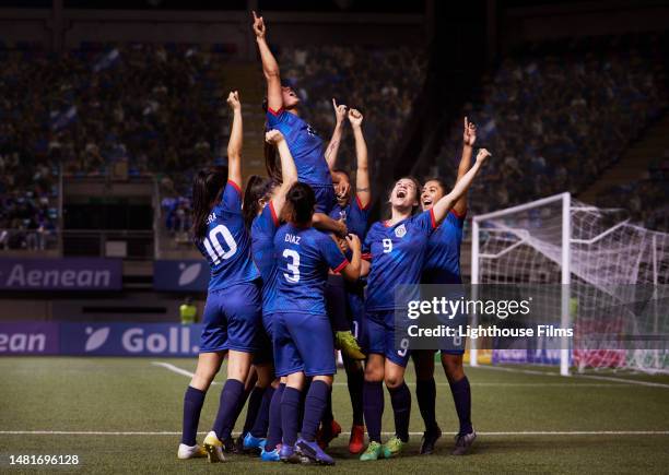 a joyful group of women soccer players raise their arms in celebration after a game winning goal. - leadership fist ストックフォトと画像