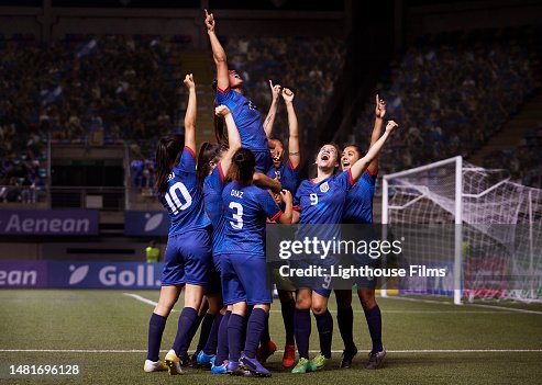 A joyful group of women soccer players raise their arms in celebration after a game winning goal. A joyful group of women soccer players raise their arms in celebration after a game winning goal.