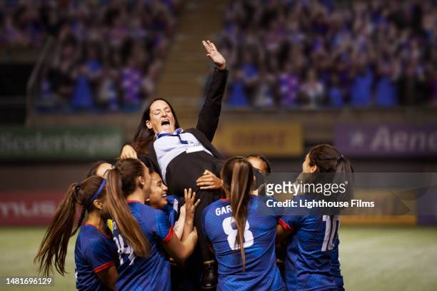 a team of soccer players lift their coach into the air to celebrate winning a championship. - sports team stock pictures, royalty-free photos & images