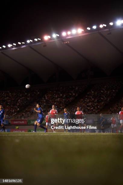 a soccer ball flys into the air as soccer team members chase after it. - fútbol femenino fotografías e imágenes de stock