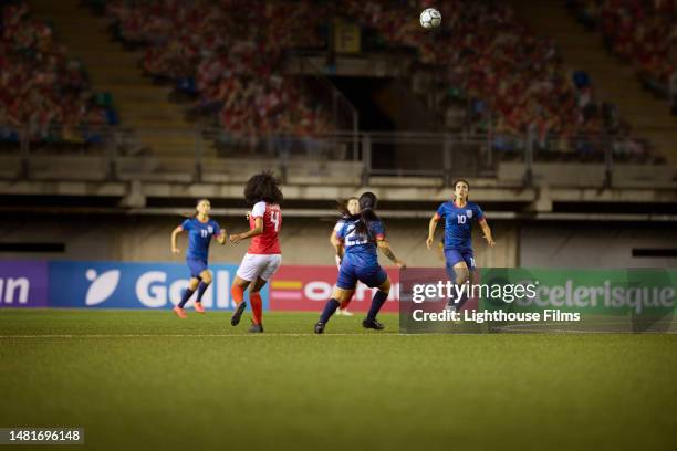 competing women soccer players battle for possession as the ball flies through the air - international race stock pictures, royalty-free photos & images