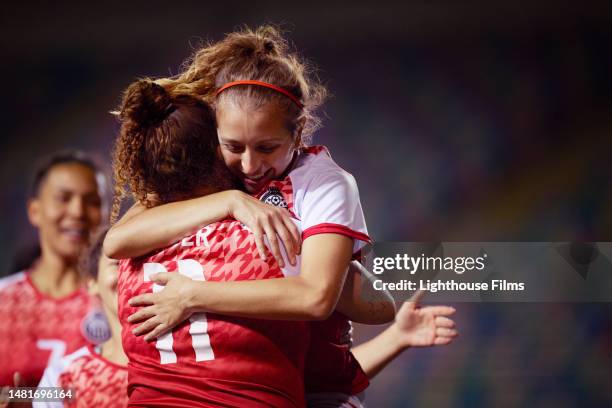 two female soccer players hug and embrace after scoring a goal - sport and team photos et images de collection