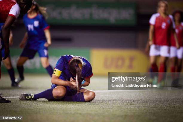 injured female soccer captain player sits on the ground after a big collision during a game - team captain stock pictures, royalty-free photos & images