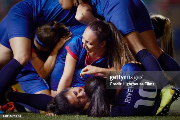 female soccer team dog pile on top of each other as they celebrate winning a game - defense player stock pictures, royalty-free photos & images