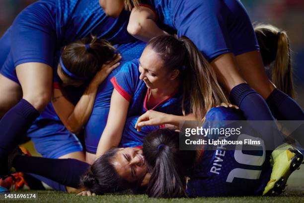female soccer team dog pile on top of each other as they celebrate winning a game - försvarare fotbollsspelare bildbanksfoton och bilder