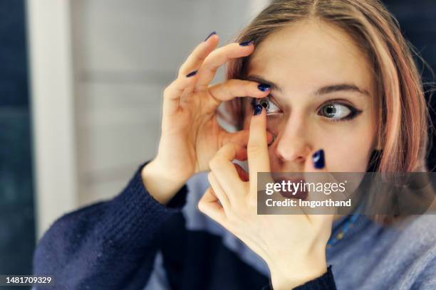 teenage girl is wearing contact lens in the bathroom - lente de contacto imagens e fotografias de stock