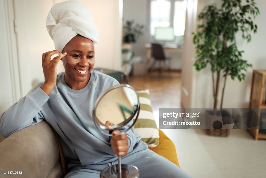 Beautiful woman applying under-eye patches at home