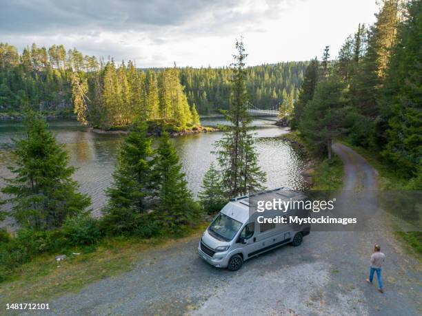 man walks towards his van parked by the lake, drone view - road trip van stock pictures, royalty-free photos & images