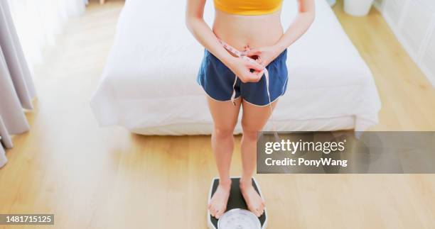 woman with tape on scale - woman measuring tape stock pictures, royalty-free photos & images