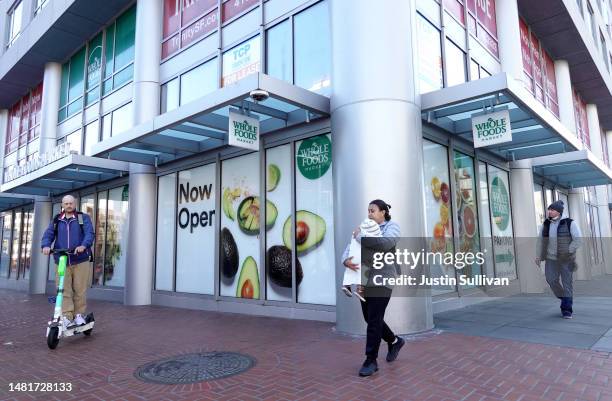Residents pass by an advertisement for a Whole Foods store on April 12, 2023 in San Francisco, California. Whole Foods has temporarily closed one of...