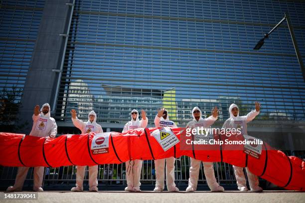 Activists dress in hazard-materials suits and hold up a mock oil pipeline while protesting against fossil fuel development supported by the...