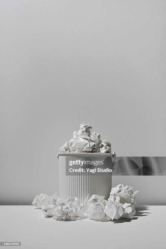 Trash can and paper trash on white background