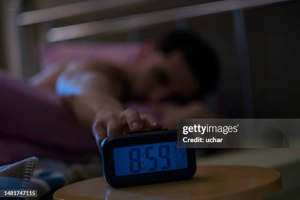 l’homme éteint le réveil au lit - réveil photos et images de collection
