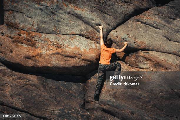 agile brave woman climbing a rocky wall - climber striving for the top - free climbing fotografías e imágenes de stock